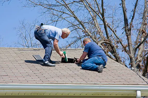Storm Damage Roof Repair Washington NC 3 Two roofers sealing a roof vent and repairing shingles on a home after storm damage