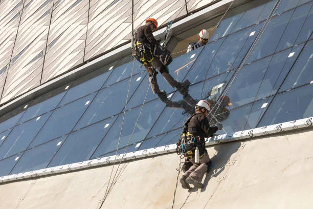 Roof Repair Washington NC 4 Rope access technicians working on the glass facade of a modern commercial building