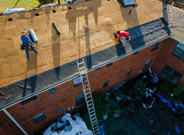 Services 1 Roofers installing underlayment over new decking on a brick building in Washington, NC